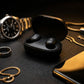 CTRL8 A6S wireless earbuds in sleek black charging case surrounded by luxury accessories on a dark surface