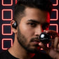 Person using CTRL8 T2 over-the-ear earbuds with UNBLOQ technology against a neon-lit background